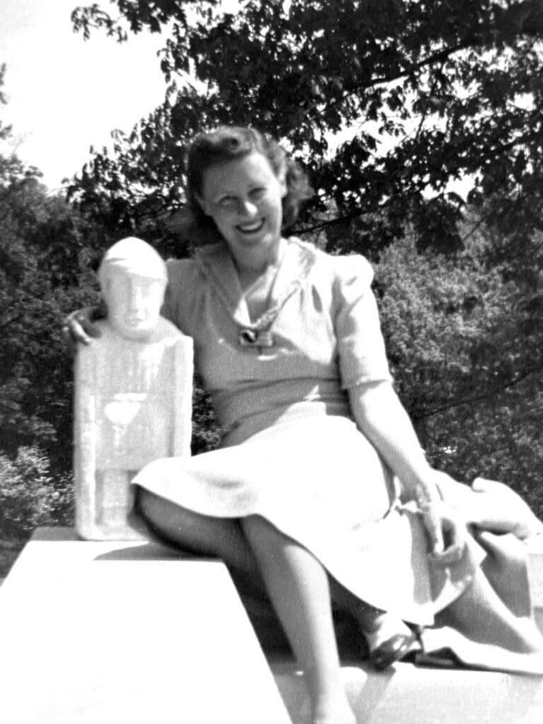 Woman in dress sits with statue.