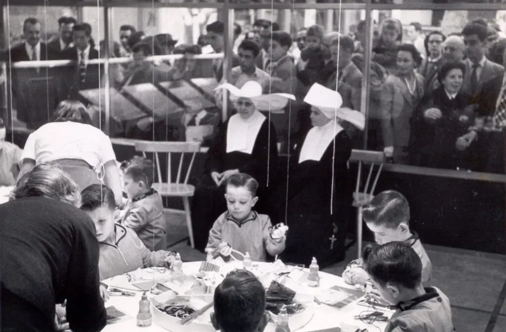 Children crafting with nuns in a room.