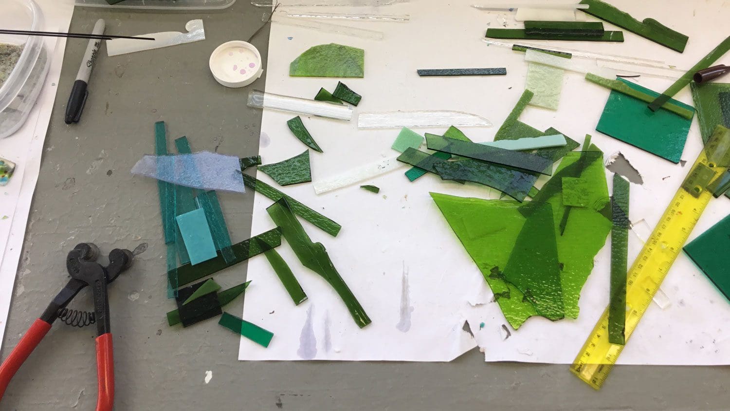 Green glass pieces on a white surface.