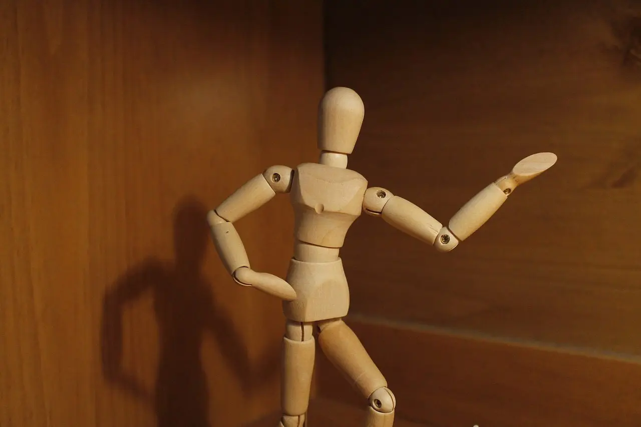 Wooden articulated doll posing on shelf.
