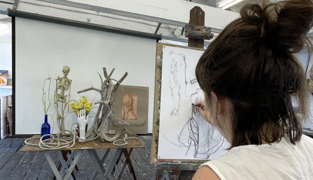 Woman sketching figure drawing in art studio.