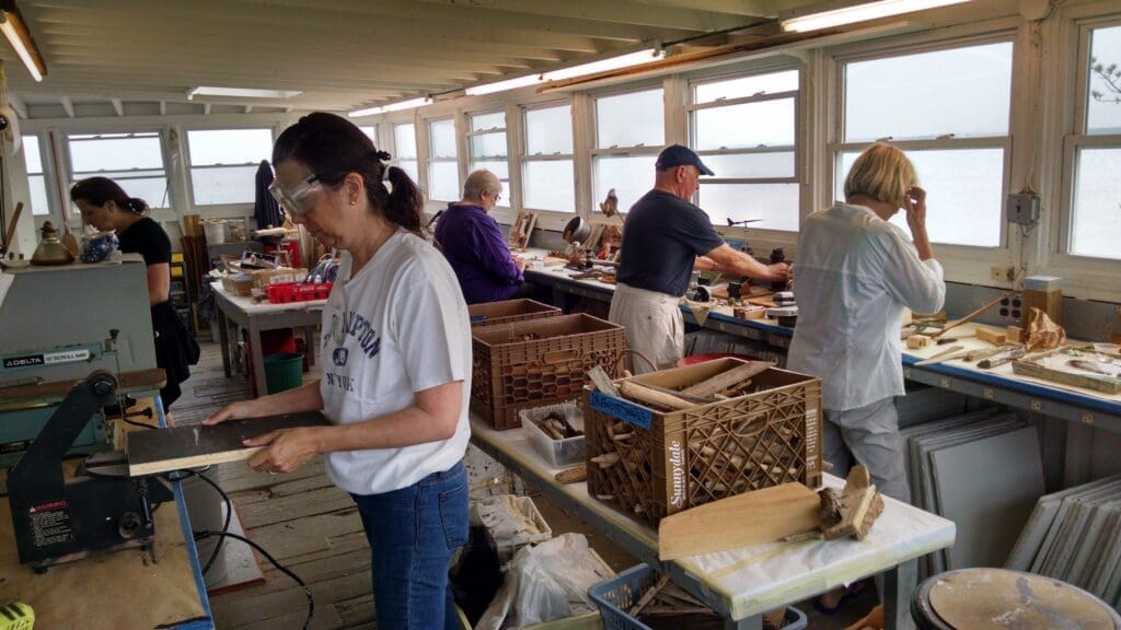 People crafting with driftwood in a workshop.